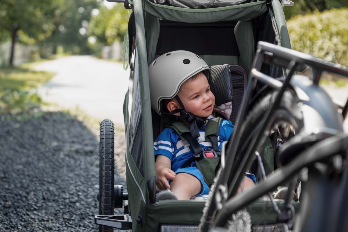 Kind mit Fahrradhelm und angelegtem Gurt im Innenraum des Kidgoo 1
